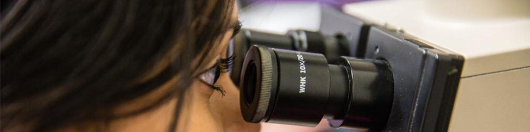 A female student looking into a microscope