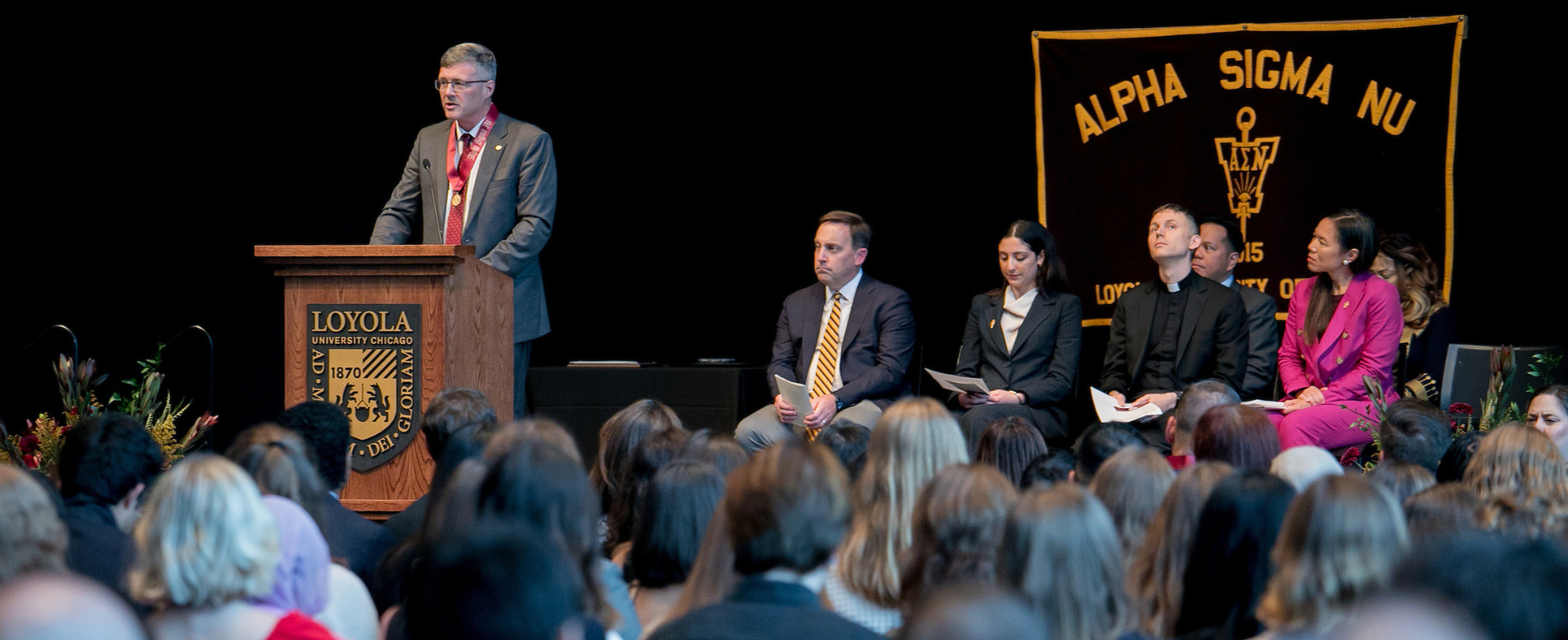 Dr. Woods speaks to the crowd of Alpha Sigma Nu inductees.