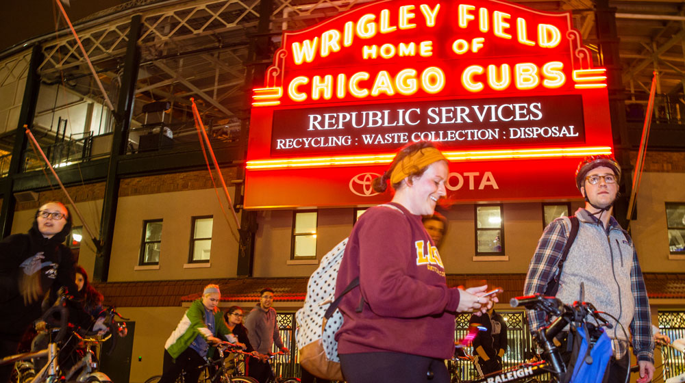 Loyola student Reed Redmond (flannel shirt) and others stop under the iconic Wrigley Field sign during a 