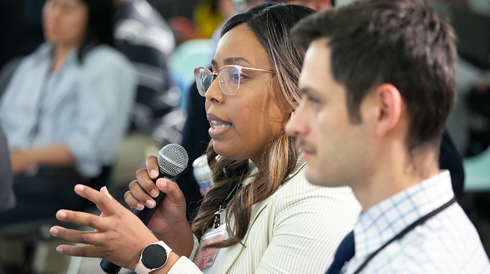 Women holding microphone with man sitting next to her.