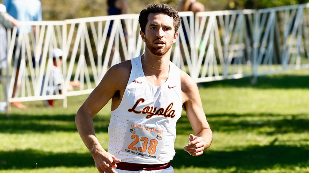 Ryan Martins in his white Loyola cross country jersey running a race