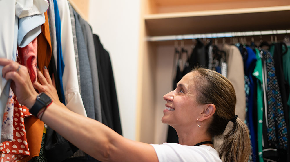 Patricia Hernandez shuffling throught clothing at the Quinlan Closet