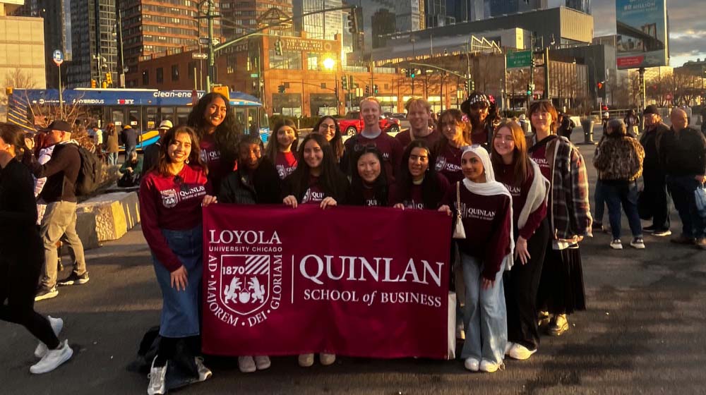 Students holding a Quinlan School of Business flag in New York City