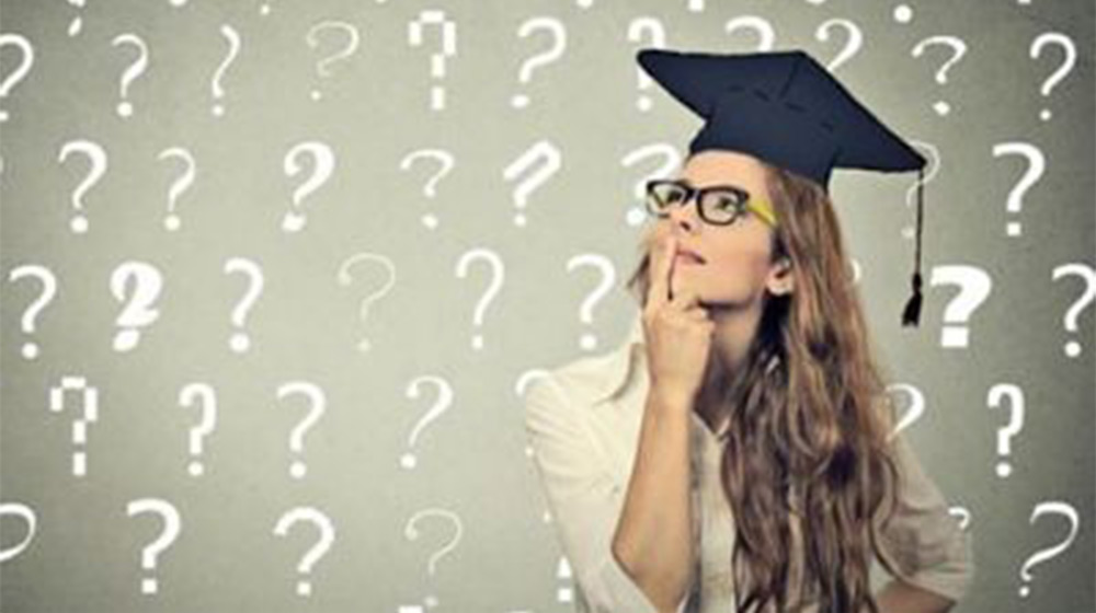 A graduate wearing a tassel and cap and glasses looks up and ponders. The image has graphics of question marks all around the person.