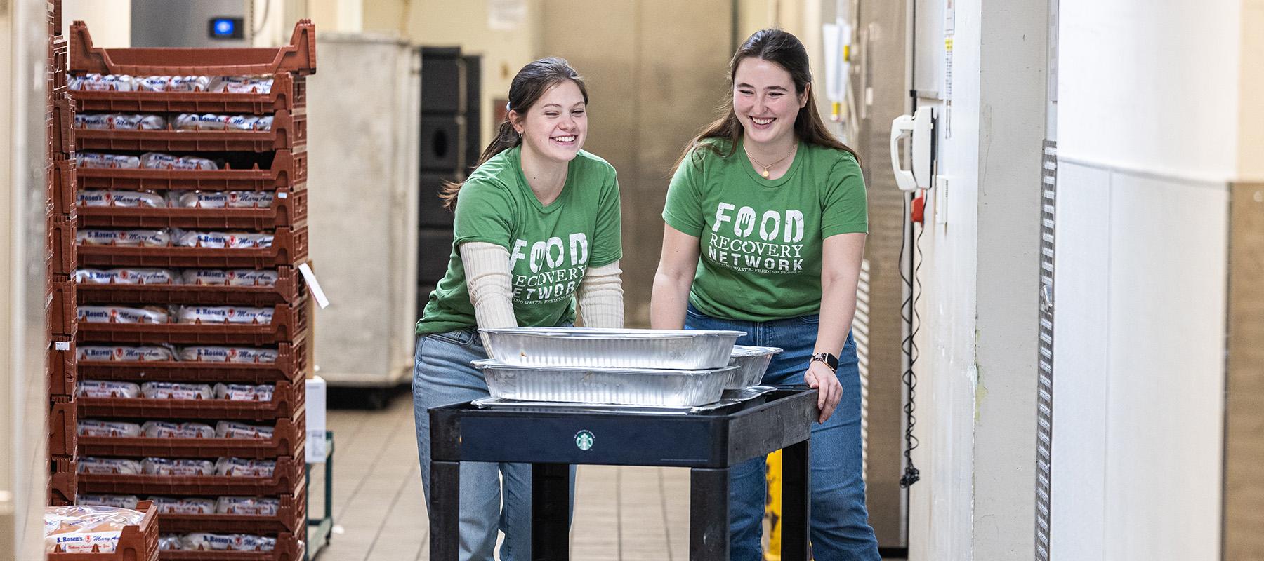 Students with a cart moving trays of food