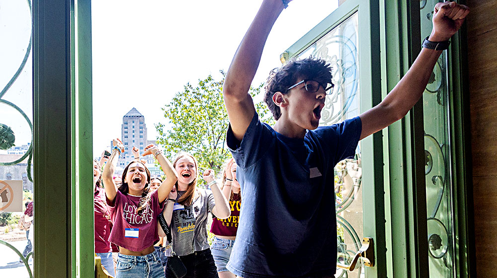 Several new Loyola University Chicago students celebrate new student convocation by walking though the iconic doors of Cudahy Library.