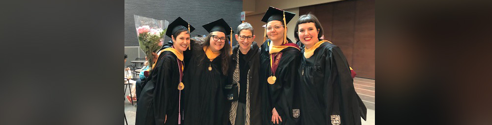 A small group of Womens Studies and Gender Studies graduates pose together in cap and gown attire.